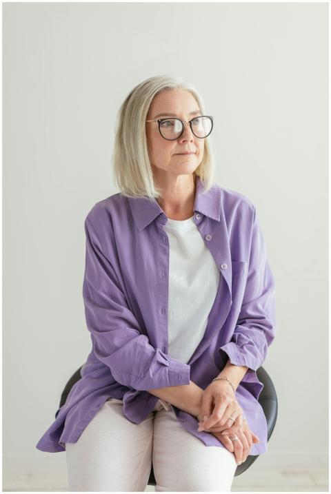 Elegant senior woman with glasses sitting indoors
