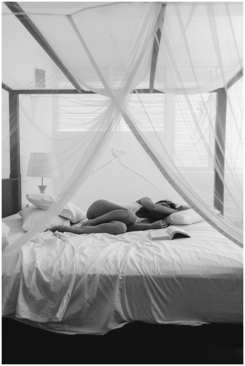 Black and white photo of a woman lying on a bed wi