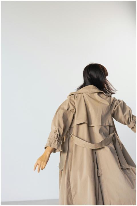 A woman with long hair is wearing a trench coat in