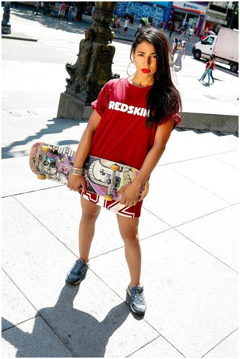 Confident young woman holding skateboard in urban