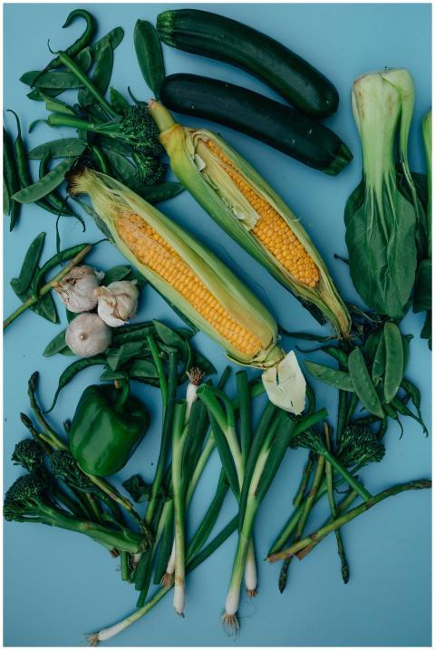 Assorted fresh green vegetables and corn on a vibr
