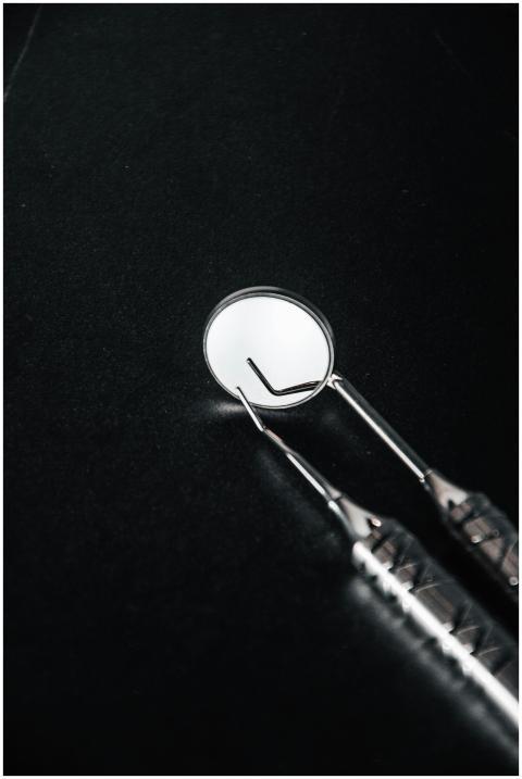 Close-up of stainless steel dental tools on a blac