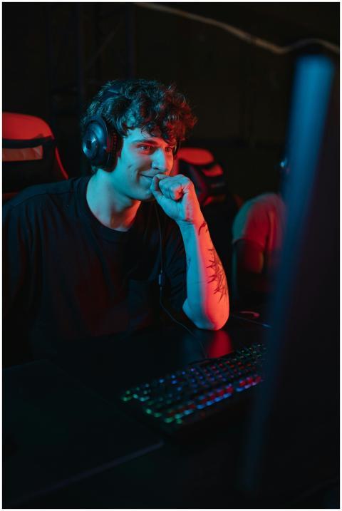 A young man sitting and gaming indoors, wearing a