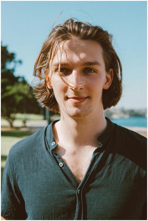 A young man with a relaxed expression, standing ou