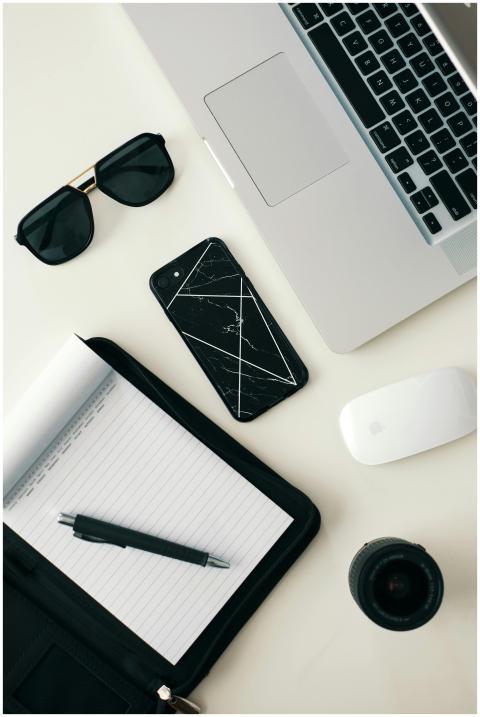 A clean workspace featuring a laptop, smartphone,