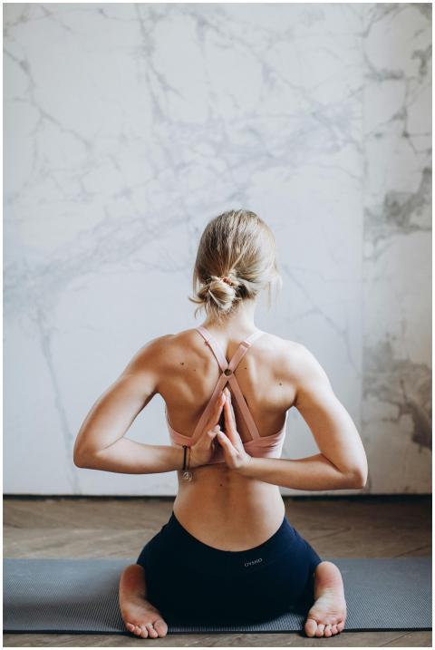 A young woman meditating indoors in reverse prayer