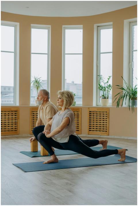 Elderly couple stretching in a yoga pose on mats i