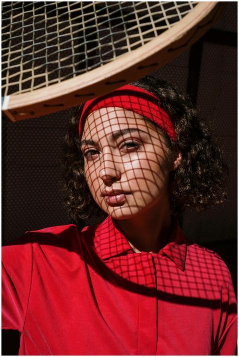 Woman in red shirt with tennis racket shadows on f