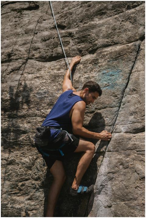 A determined man climbs a rugged cliff face using