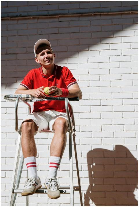 Smiling tennis umpire in red polo sitting on chair