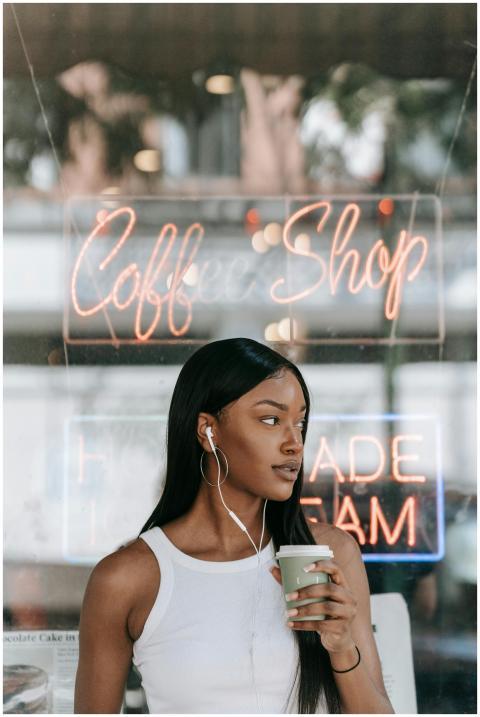 African American woman with headphones holding cof
