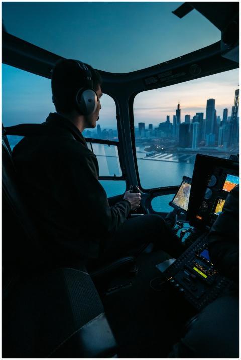 Pilot flying a helicopter over Chicago with skylin