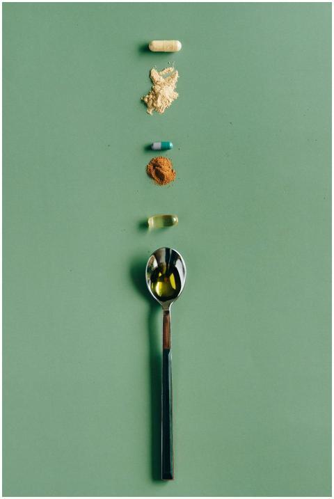 Assorted supplements and a spoon laid out on a gre