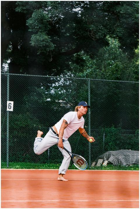 Young male tennis player serving on an outdoor cla