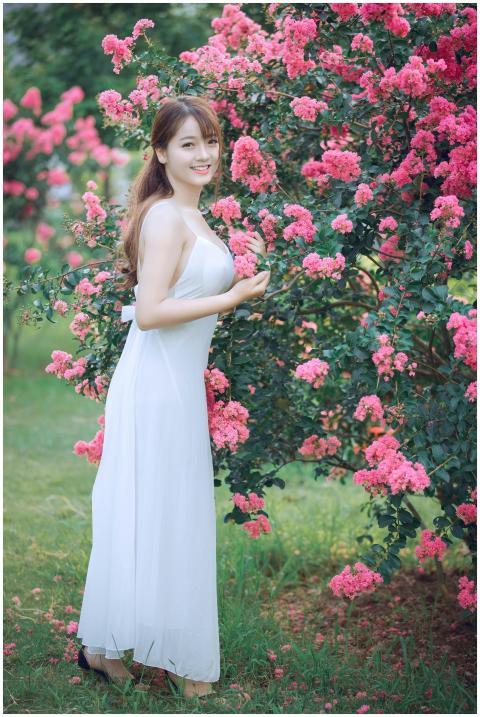 Beautiful woman in a white dress posing by vibrant