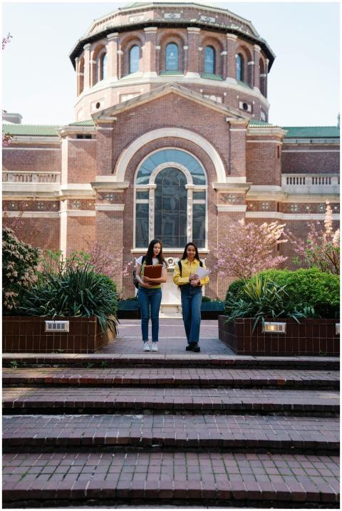 Two young women walking past a historic university