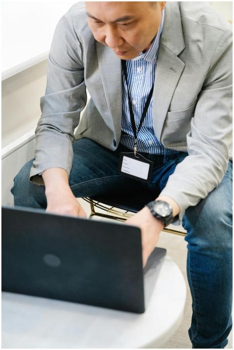 Adult businessman wearing a gray blazer typing on