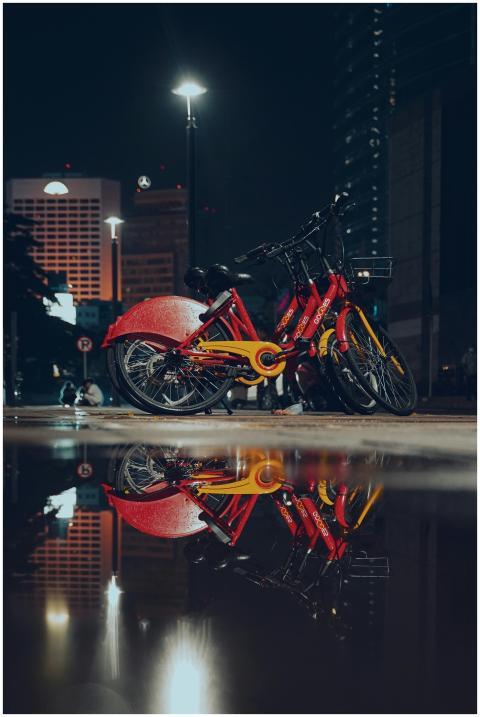 Urban bicycles reflecting in a puddle at night, wi