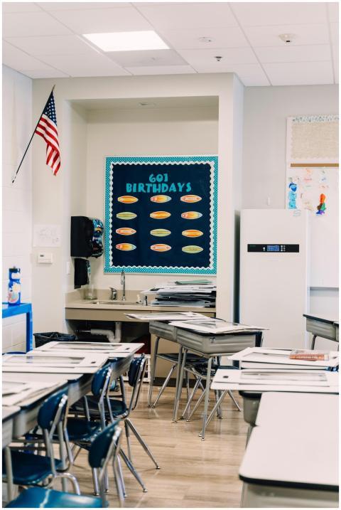 A well-lit classroom with desks, chairs, and a bir