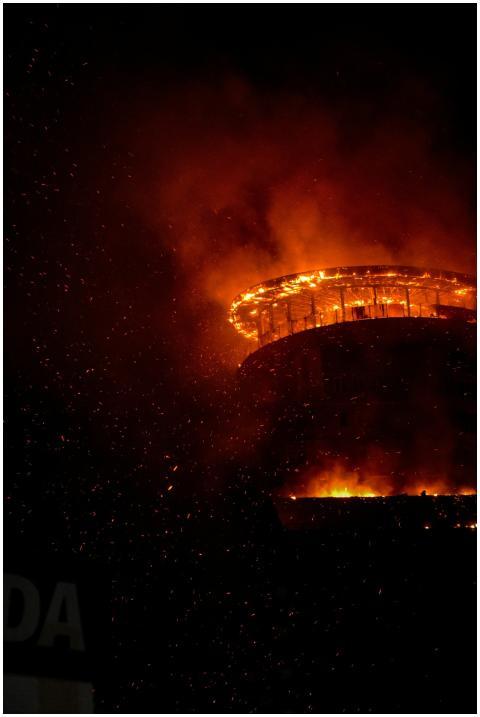 A towering structure engulfed in flames at night,