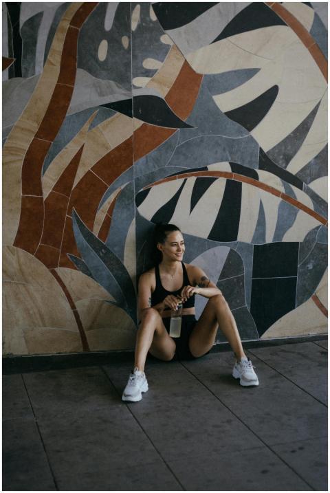 Woman in athletic wear resting against a colorful