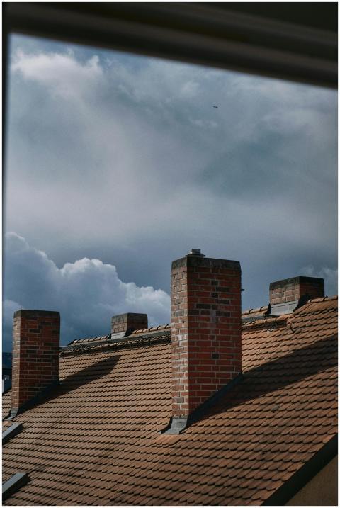 A dramatic view of brick chimneys on a tiled roof