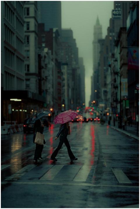 Two people crossing a rainy New York street with u