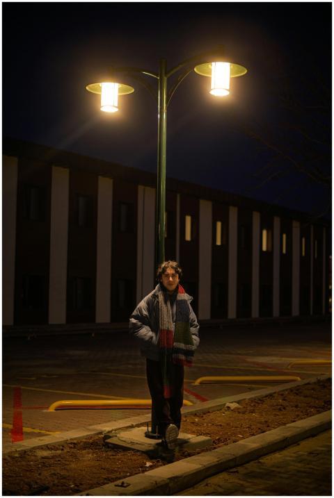 Person leaning on lamp post illuminating a parking