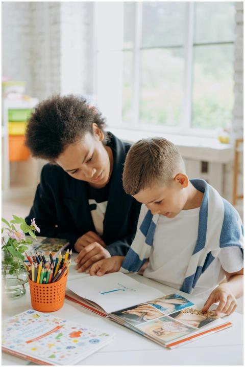A teacher helps a student read a book in a bright