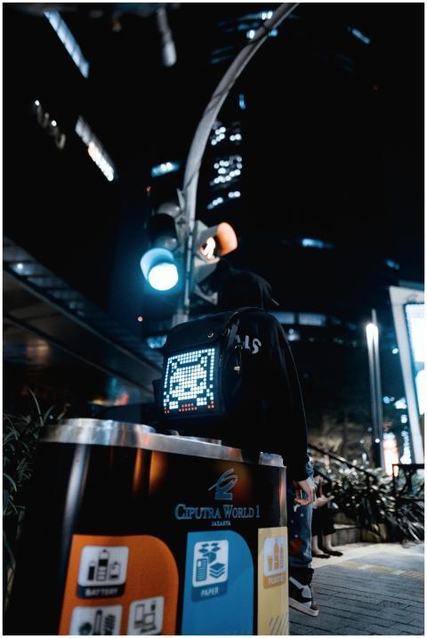 A person with a digital pixel art backpack stands