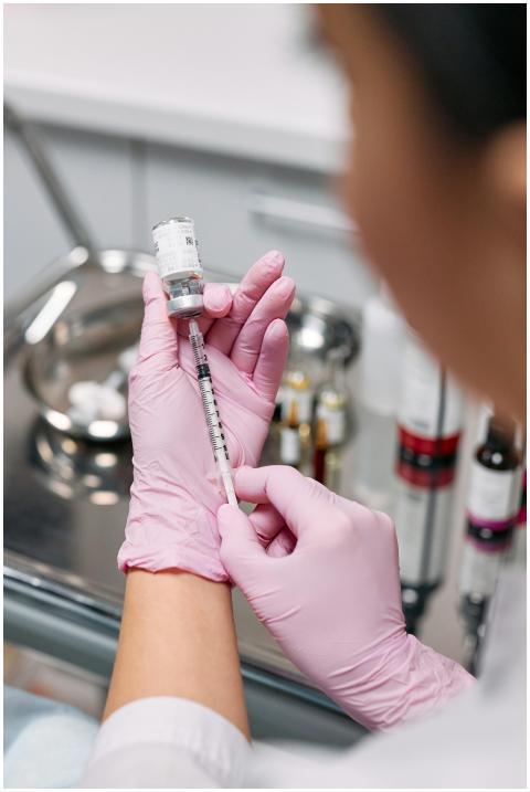 A healthcare worker wearing gloves prepares a syri