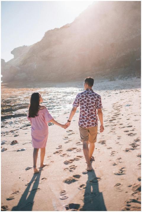 Young couple strolling hand in hand on a sunny bea
