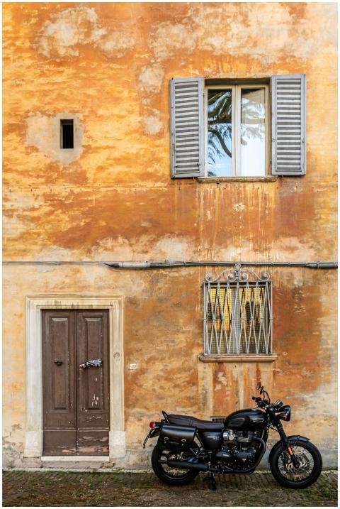 A classic motorcycle parked by a weathered wall in