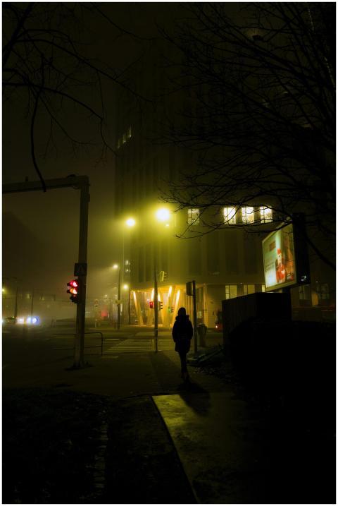 A solitary figure walks through a foggy, illuminat