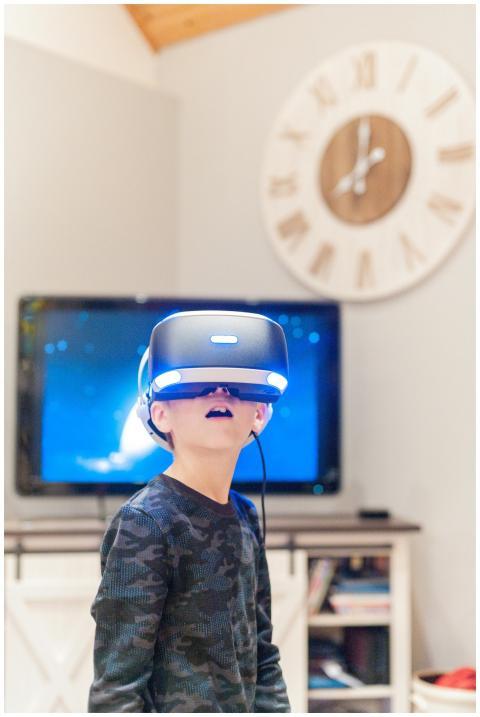 Curious little boy in VR goggles and casual clothe