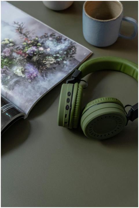 Green headphones and magazine on a table with a mu