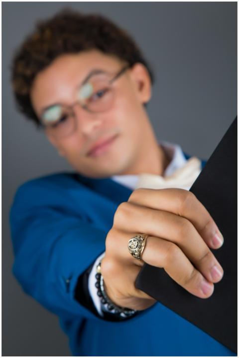 Young graduate in blue suit proudly displaying dip