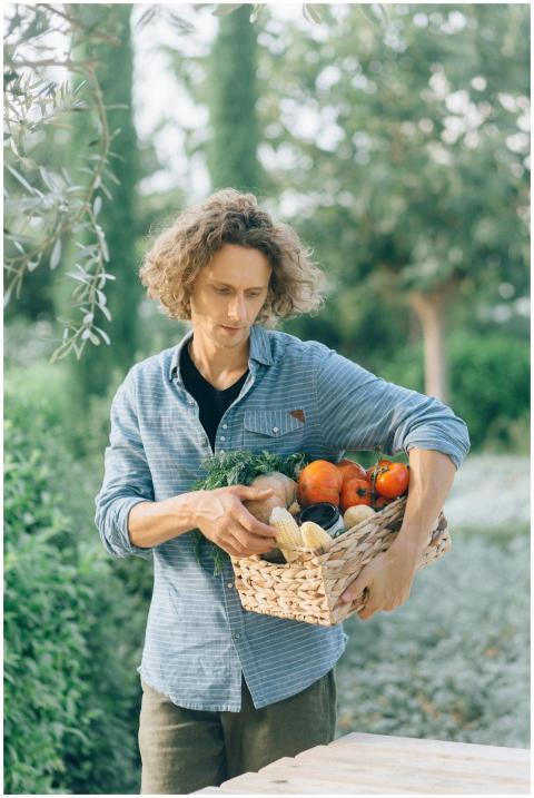 A man holding a woven basket filled with fresh pro
