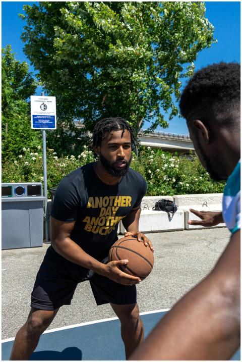Two men playing basketball outdoors on a sunny day