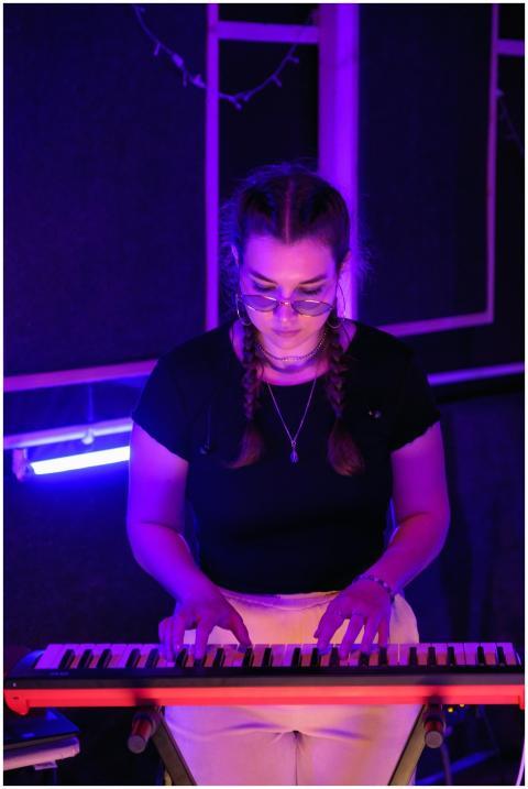 Woman playing keyboard instrument in a vibrant pur