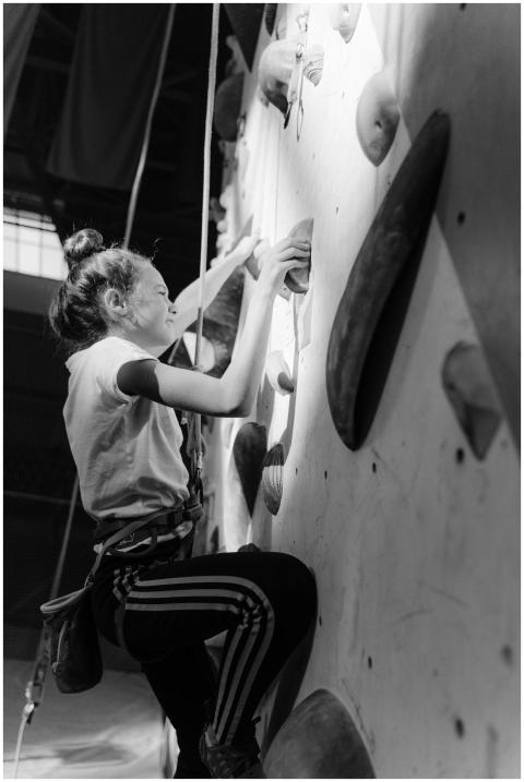 Teenage girl rock climbing indoors, showcasing det