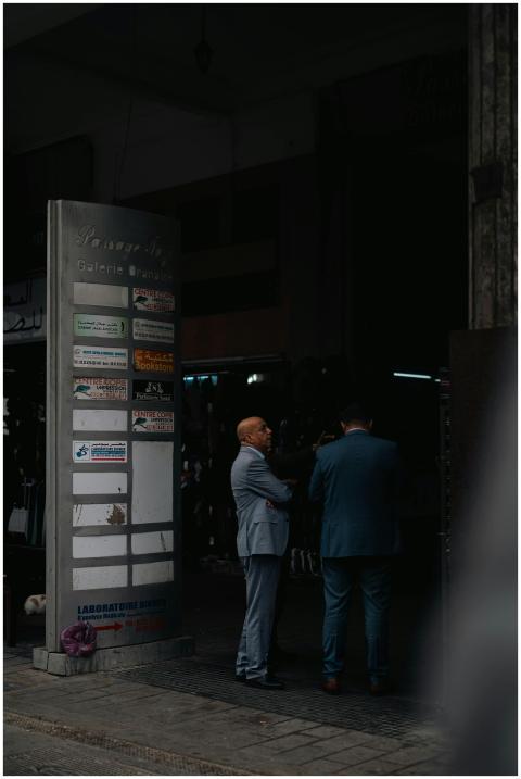 Two businessmen in suits engage in conversation ou