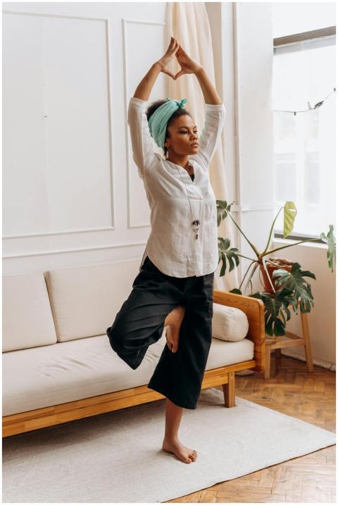 An adult black woman practicing yoga at home in a