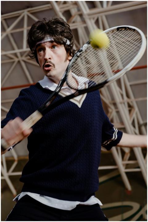 A young adult male tennis player energetically ret