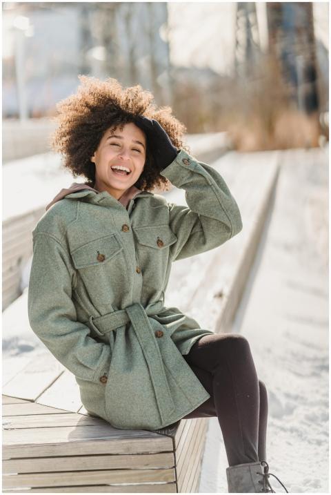 Happy young ethnic female wearing warm coat touchi