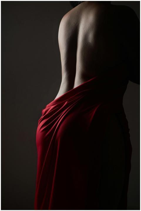 Moody silhouette of a person draped in red fabric,