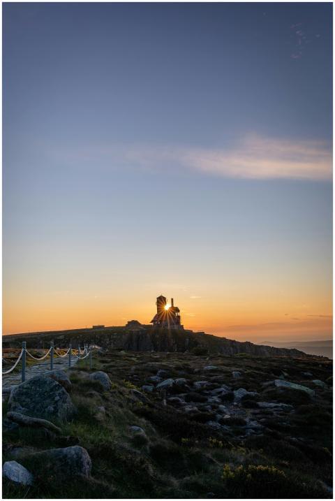 Scenic view of a lighthouse on a mountain at sunse