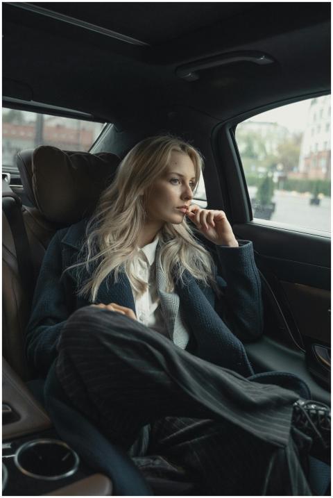 A thoughtful businesswoman sits in a luxurious car