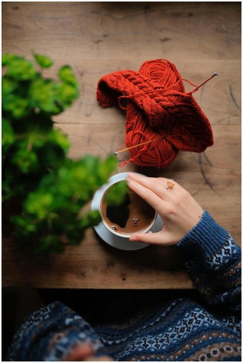 A person enjoying coffee with knitting materials,