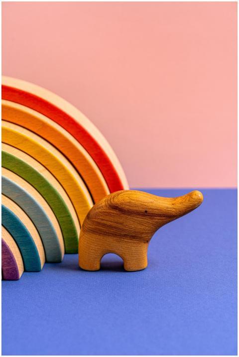 A wooden elephant figurine with a colorful rainbow